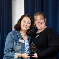 Two women holding an award